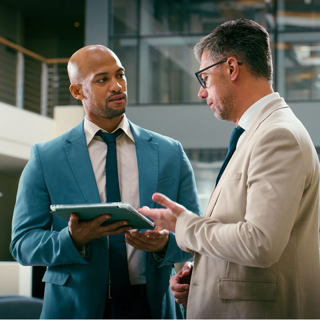 Two businessmen discussing work indoors.
