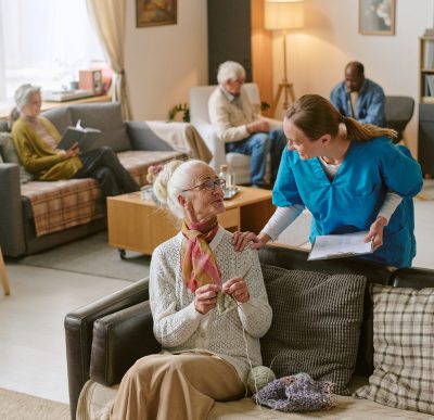 Elderly woman knitting in common room
