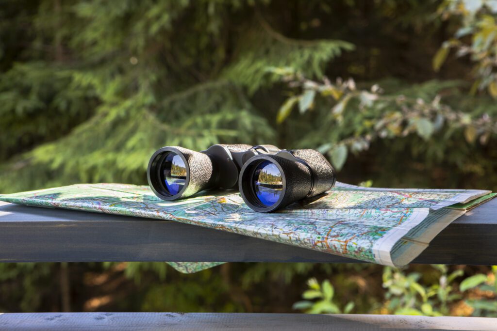 Binoculars resting on a map outdoors