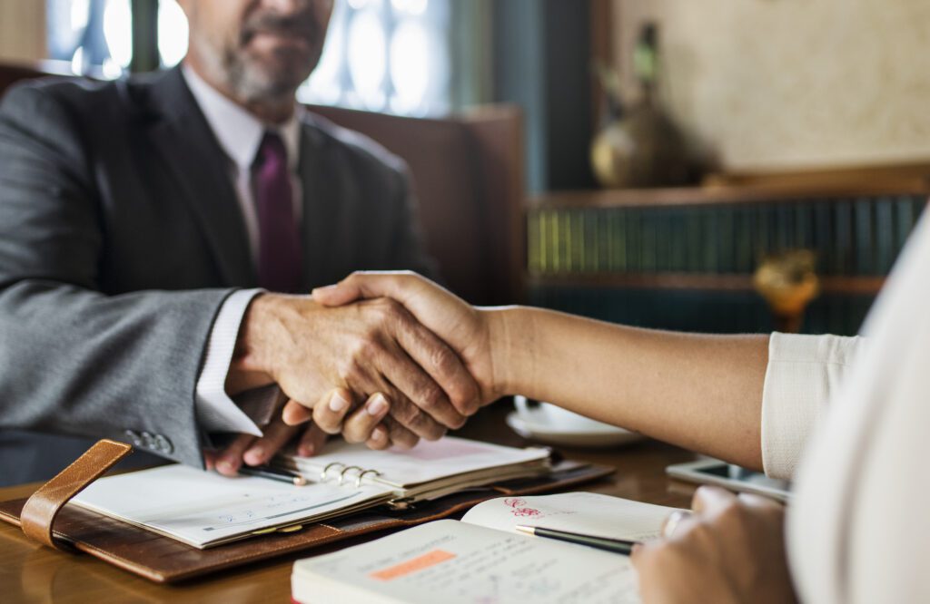 Two professionals shake hands across desk