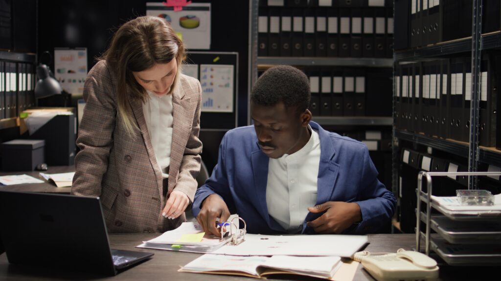 Two coworkers reviewing documents in server room.
