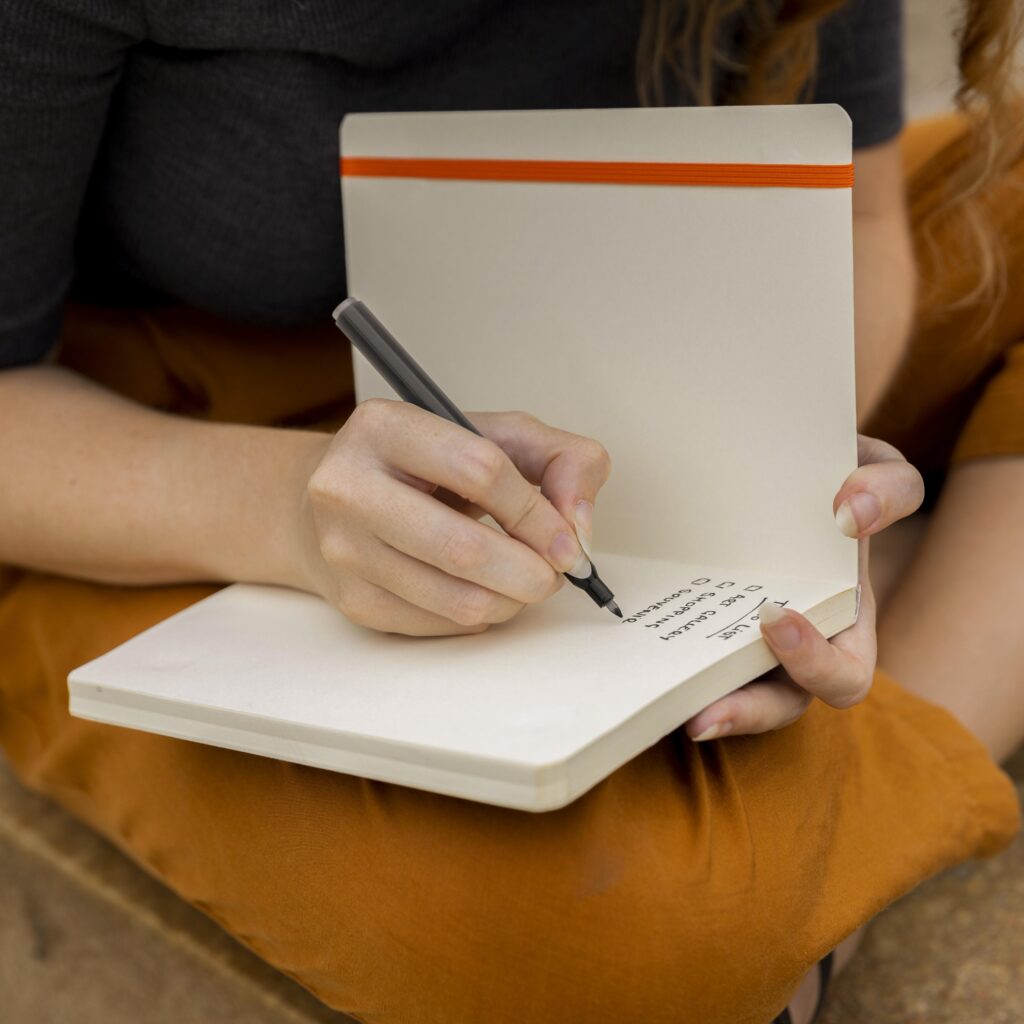 Hands writing in a blank notebook.