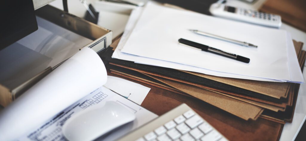 Cluttered desk with papers and pens