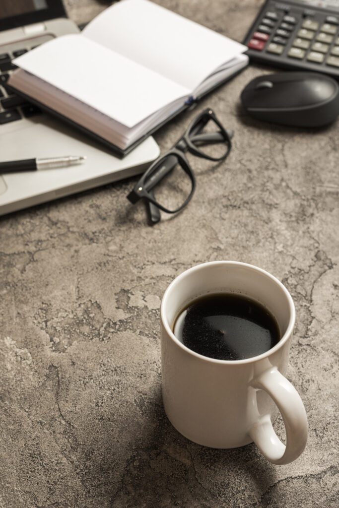 Coffee mug on desk with notebook and glasses